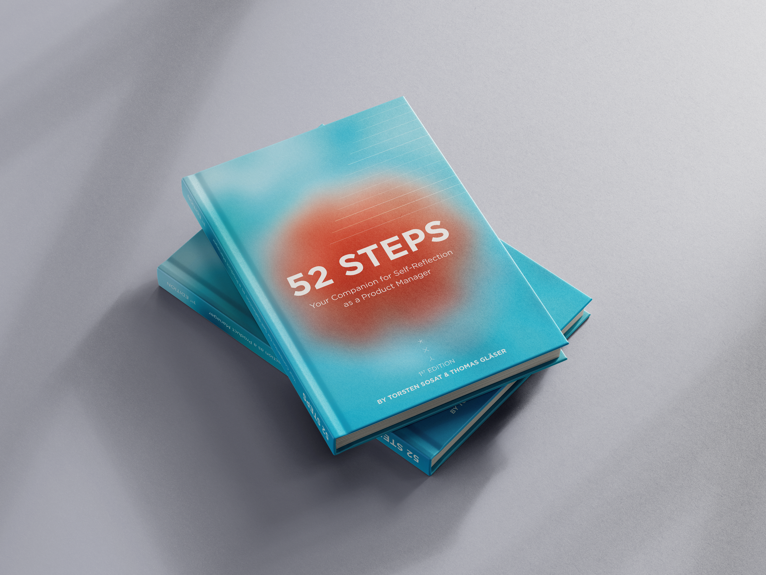 Two blue books titled "52 Steps" placed on a light gray surface, with one book on top of the other, slightly angled. The cover features a gradient background with a central orange blurred circle.
